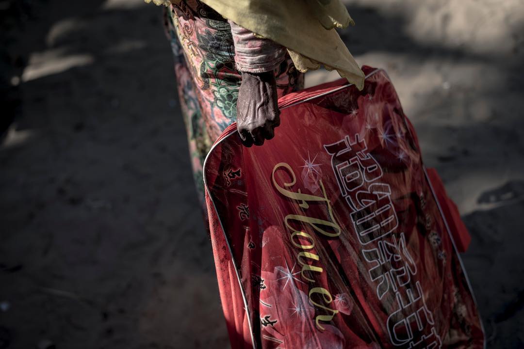 An elderly Rohingyan woman stand with all of her belongings. She arrived in Bangladesh during the Night and now awaits gettong transported to the camps