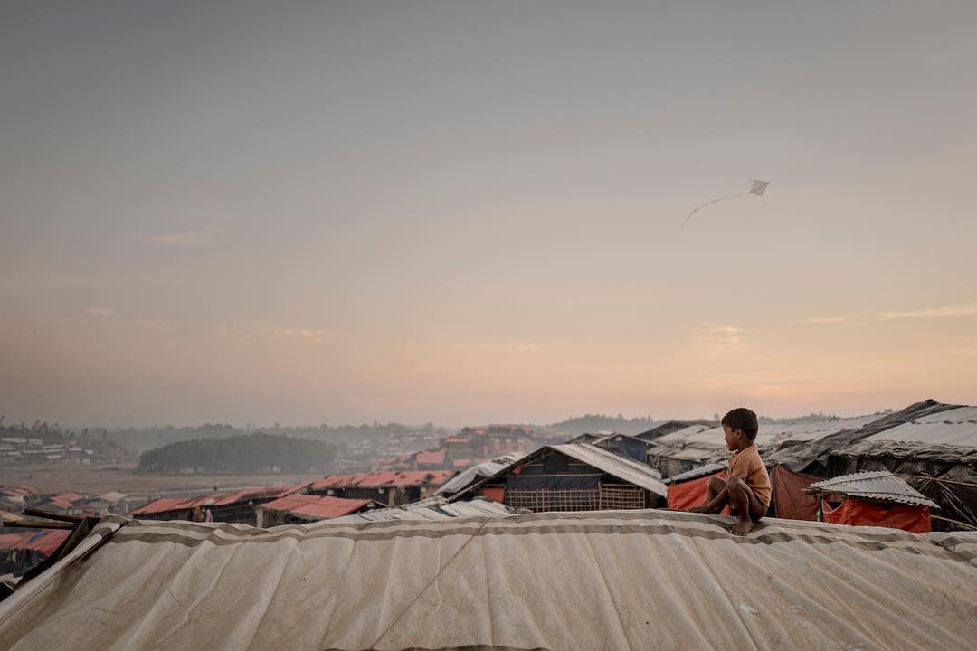 A Rohingyan boy sits ontop of a makeshift tent in Jamtoli refugee camp