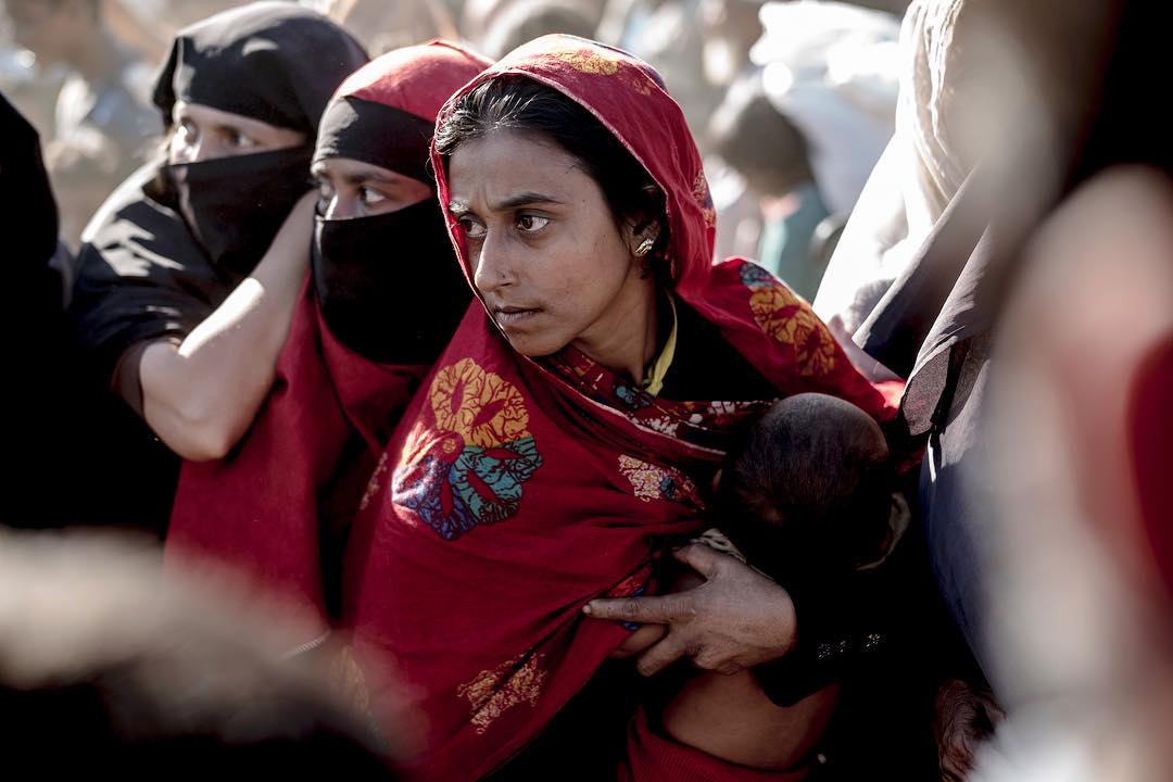 A Rohingyan woman protects her child and her spot as fighting breaks out in the que for life vital aid delivery. Kutupalong Refugeecamp @reduxpictures